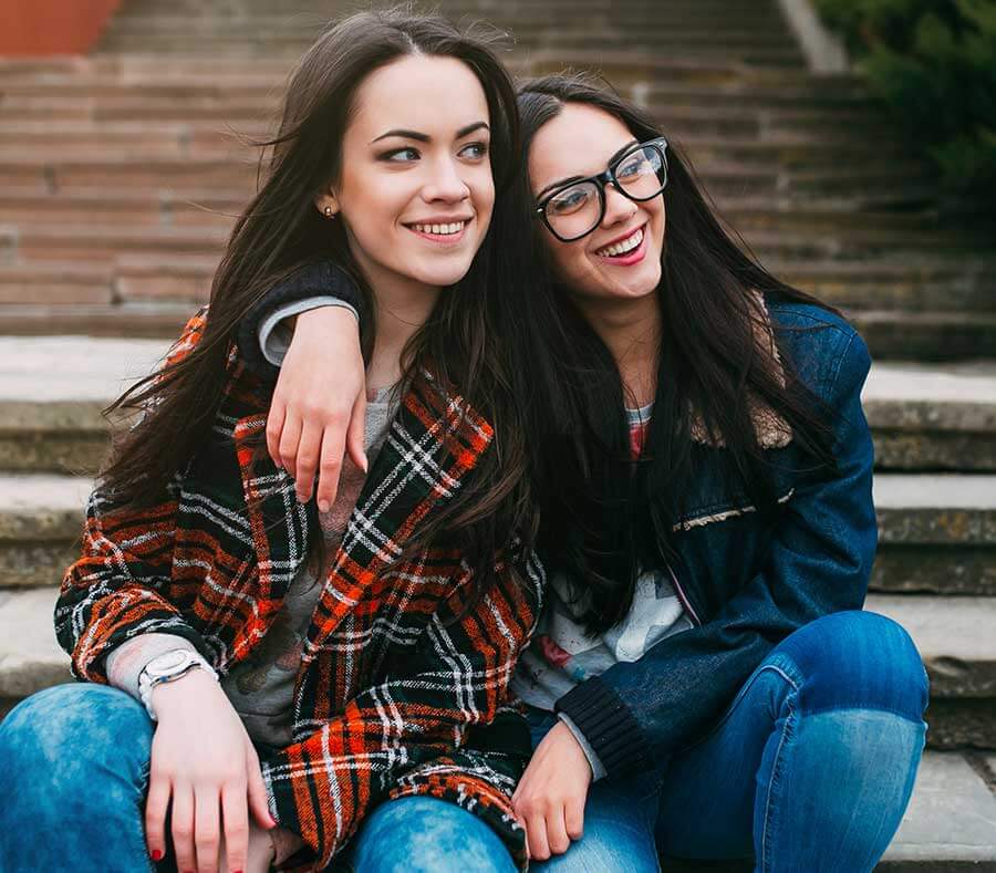 two teen girls smiling on the steps in their treatment program