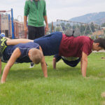 teen males do team pushups with an instructor