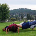 teen boys do team pushups in a soccer field