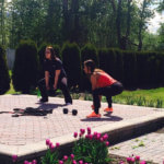 two teen girls lift weights outside