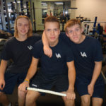 three teen males bond in a gym