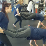 girls support partners as they wheelbarrow walk in a gym