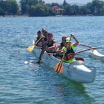 group of teens paddle a canoe in the water