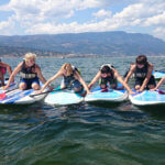 teens creating a line of surfboards in the water