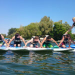 teens holding surfboards so that a teen can run across them in the water