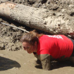 Photo Gallery: Mud-Covered Teen Crawling Under Log During Mudd, Sweat, and Tears Event