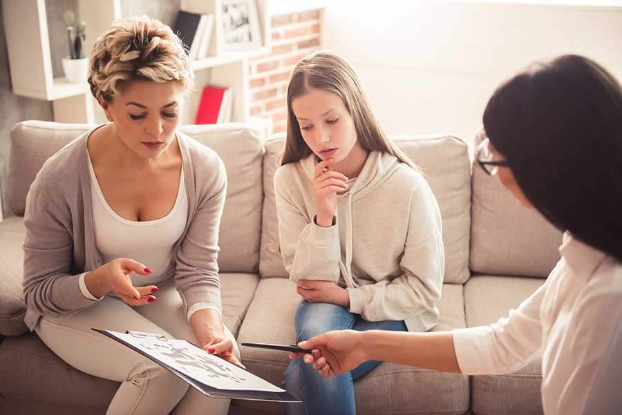 a mom with her daughter and a counselor go over the behaviour treatment program description