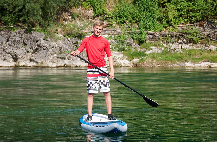 a boy paddleboards in the middle of a lake during behaviour treatment recreation