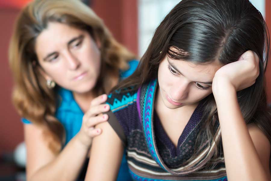 a concerned mom reassures a young girl as she listens to what parents are saying