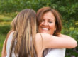 a mom smiles as she hugs her teen since they went over the bridge over troubled water