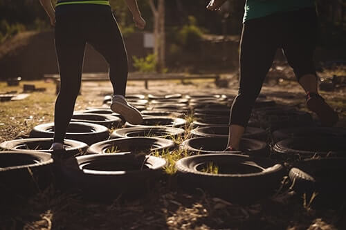 two girls in leggings run through tires at boot camp for troubled teens