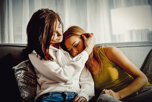 a daughter leans on a mom's shoulder while the mom contemplates how long should i wait to get help
