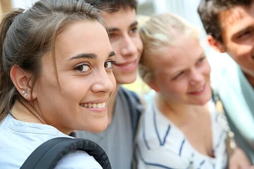three teens look away while focused girl enjoys treatment over school