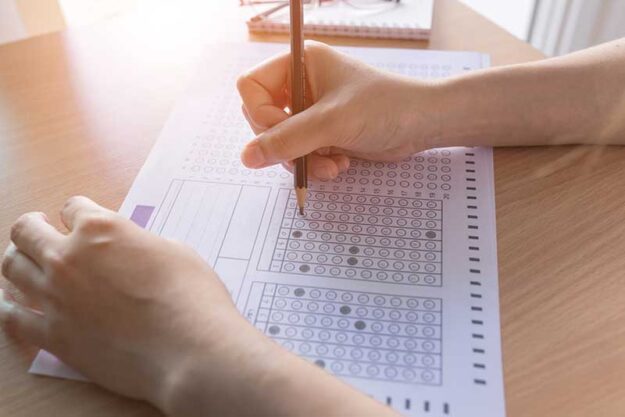 a teen fills out a test on a scantron at school