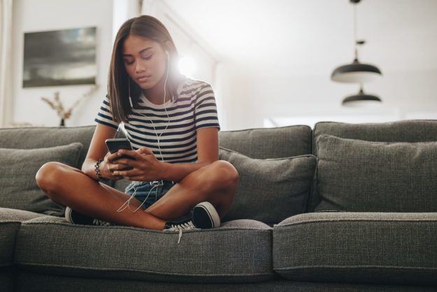 a teen spends hours on her phone on the couch at the risk of her social relationships