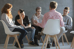 counselor and patients sit in a circle for group therapy