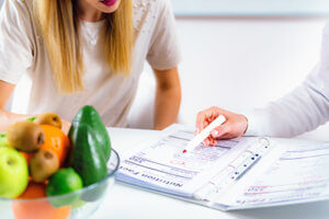 therapist points out meal plans in a book to female patient in nutritional therapy