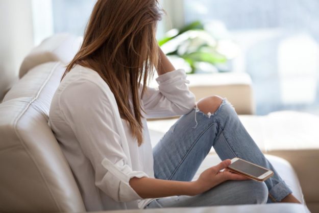 person-on-couch-holding-phone-feeling-high-functioning-anxiety