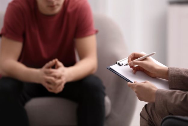 a teen boy talks to a therapist at a drug and alcohol centre