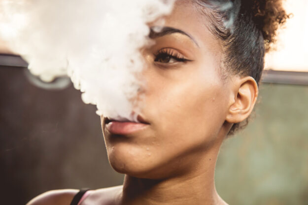 a teen blows out a cloud of cannabis smoke